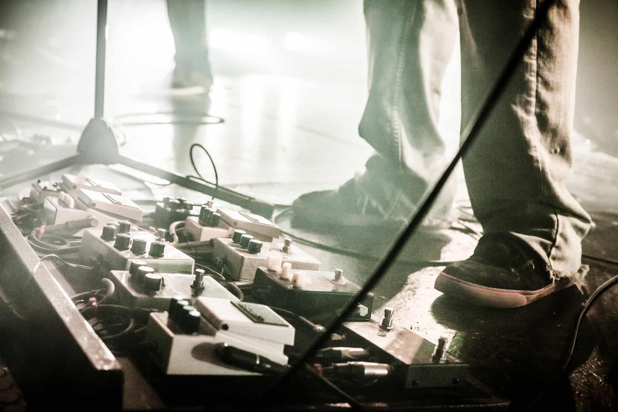 Pedais de guitarra em um palco com banda ao vivo durante um show